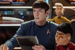 Spock holds a datapad while sitting next to a puppet of Ortegas in Star Trek Strange New Worlds