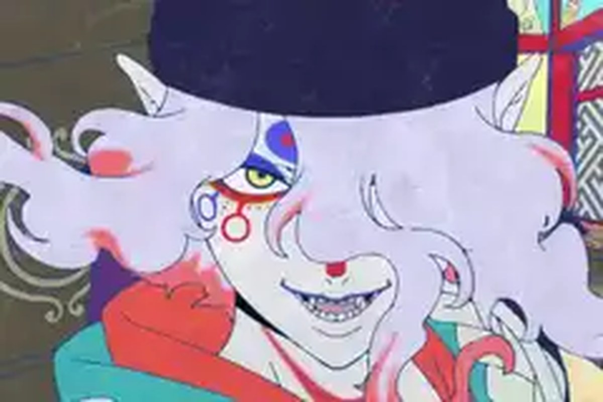 A pale-faced anime man with pink and red hair, with strange symbols and fanged teeth smiling in the trailer for the Mononoke movie.