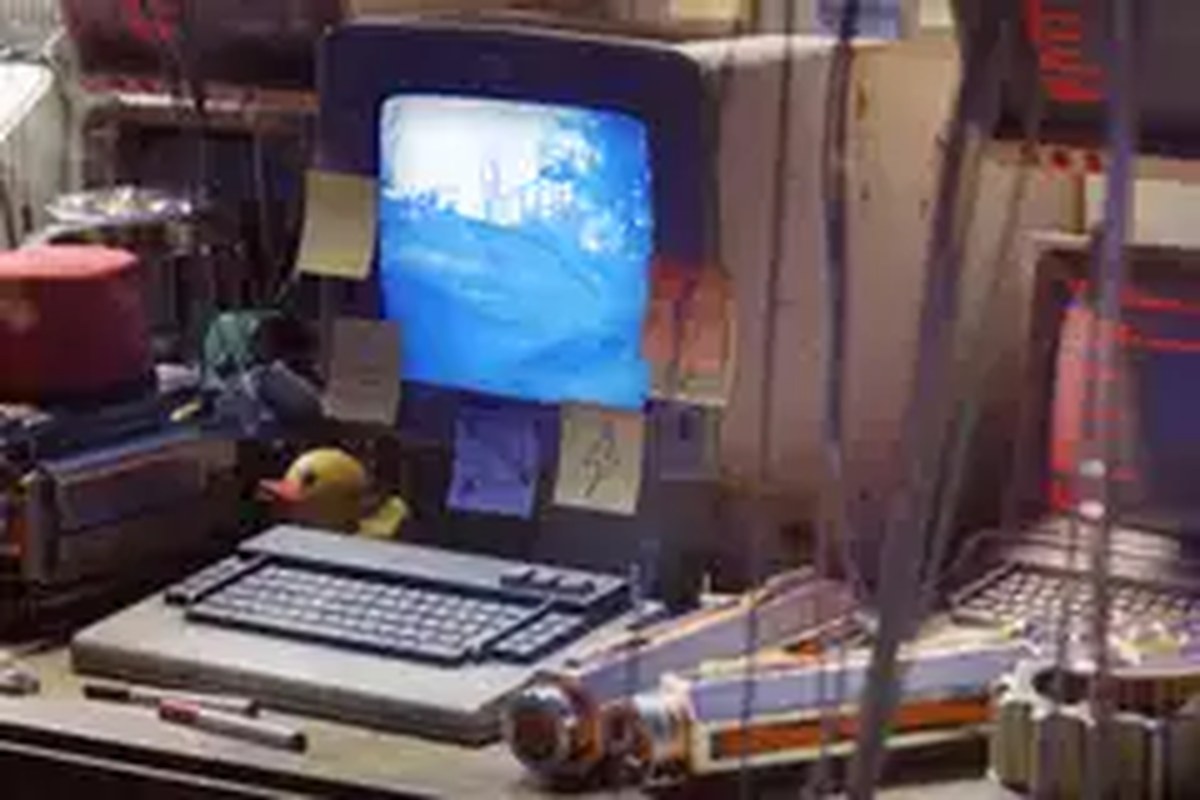 An old computer covered in post it notes on a desk littered with mechanical parts from Arc Raiders.