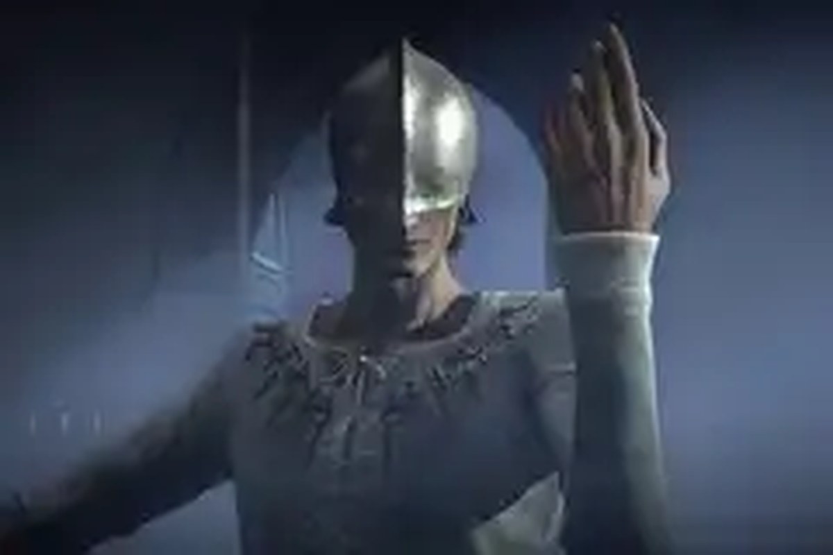 A man wearing a helmet over his eyes holds the back of his hand up to the viewer