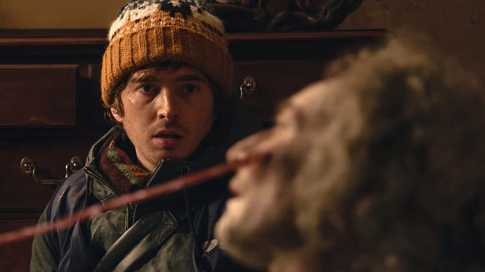 Resident Evil movie still showing bobble-hatted protagonist Bryan looking on as a tentacle emerges from a zombie's face.