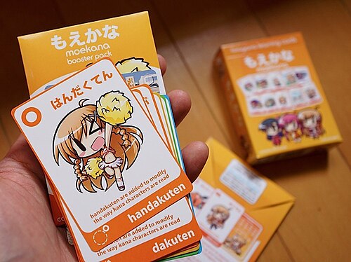 An open cardboard booster pack for the Moekana educational card game, revealing nine additional cards for the game.
